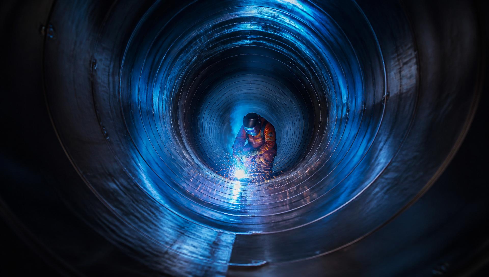 Welder inside a large steel pipeline
